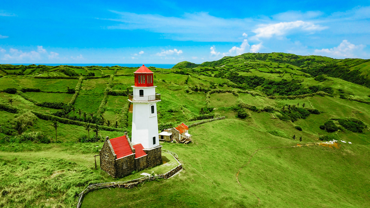 Drone shot of Mahatao Tayid Lighthouse on top rolling hills in the province of Batanes, Philippines